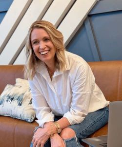 Julie smiling on a brown couch